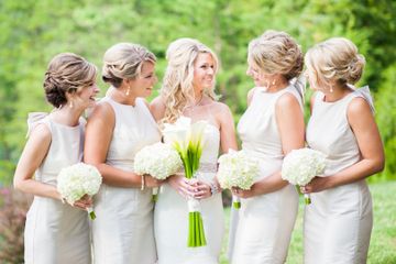 Bride and bridesmaids in white dresses with classic updos outdoors