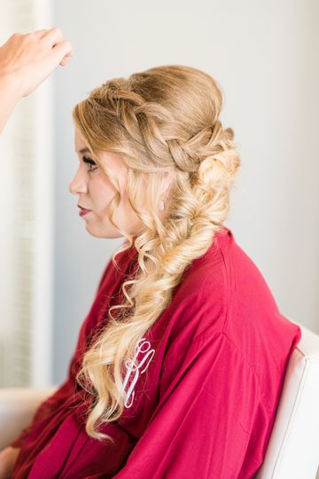 A stylist braiding a bride’s hair during a preview session
