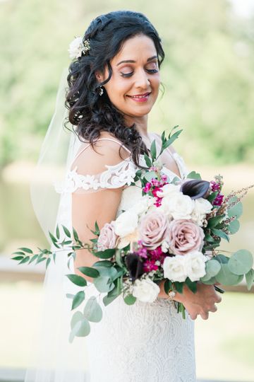 Brunette bride with a soft veiled updo holding a lush blush-and-burgundy bouquet
